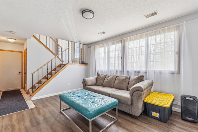 living area featuring a textured ceiling, visible vents, wood finished floors, and stairway