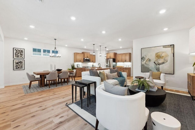 living room featuring recessed lighting, light wood finished floors, baseboards, and a chandelier
