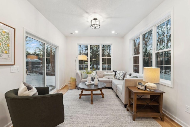 living area with baseboards, recessed lighting, and light wood-style flooring