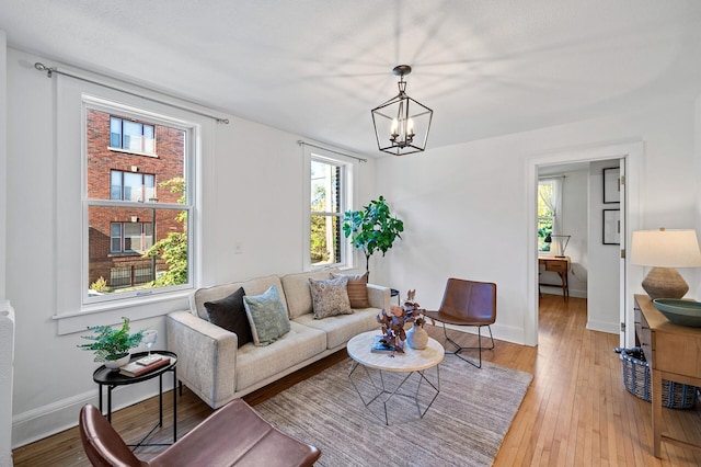 living room featuring light wood-type flooring, baseboards, and a notable chandelier