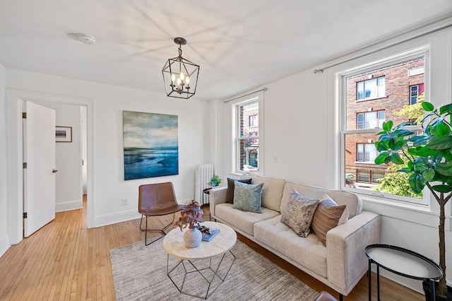 living area featuring an inviting chandelier, radiator, baseboards, and light wood-type flooring