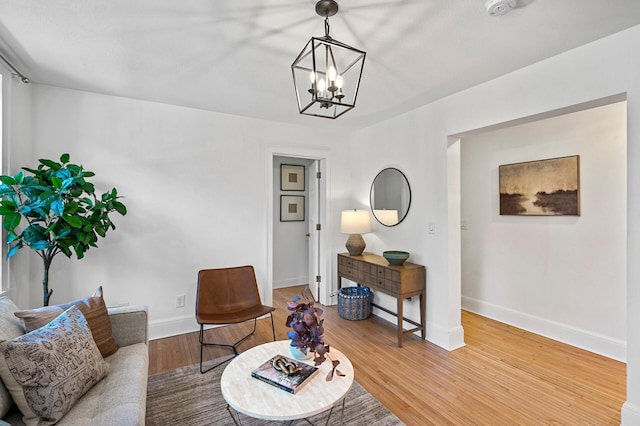 living area with baseboards, wood finished floors, and a chandelier