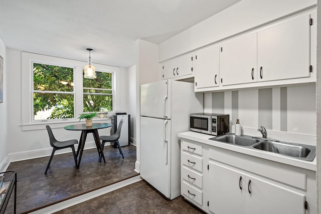 kitchen featuring baseboards, light countertops, stainless steel microwave, white cabinets, and a sink