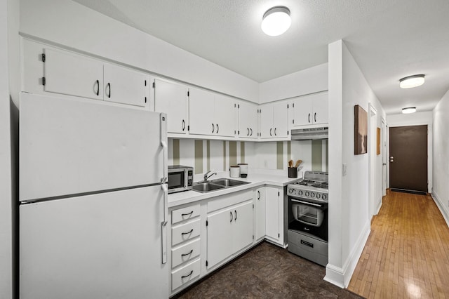 kitchen featuring baseboards, white cabinetry, under cabinet range hood, a sink, and stainless steel appliances