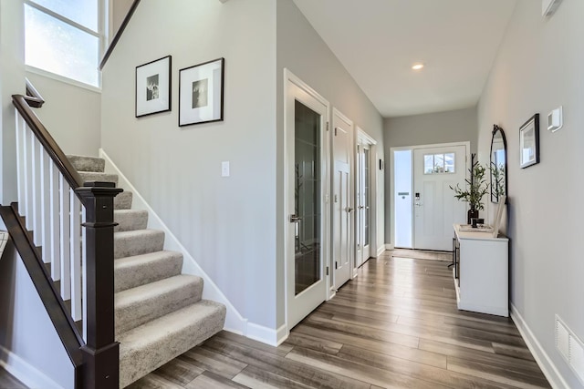 foyer entrance featuring visible vents, dark wood-style flooring, baseboards, stairway, and recessed lighting