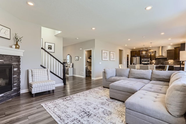 living room with recessed lighting, a stone fireplace, dark wood-style floors, and stairway