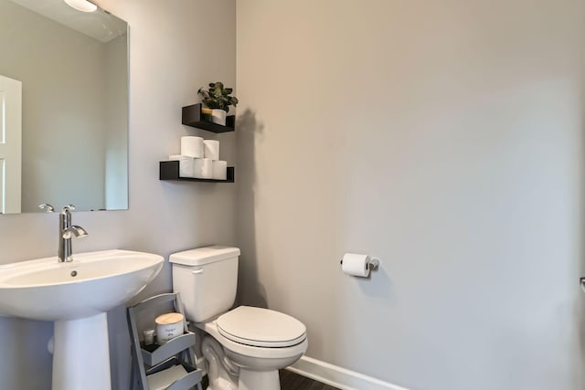 bathroom with toilet, baseboards, a sink, and wood finished floors