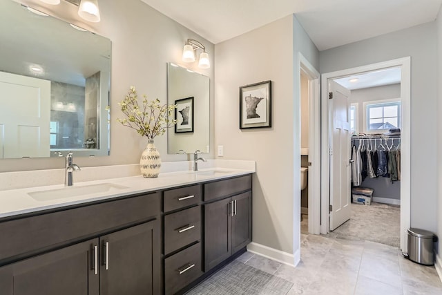 bathroom featuring double vanity, a sink, baseboards, and walk in shower