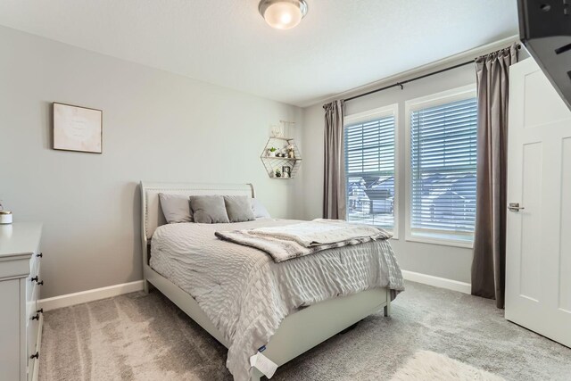 bedroom with baseboards and light carpet