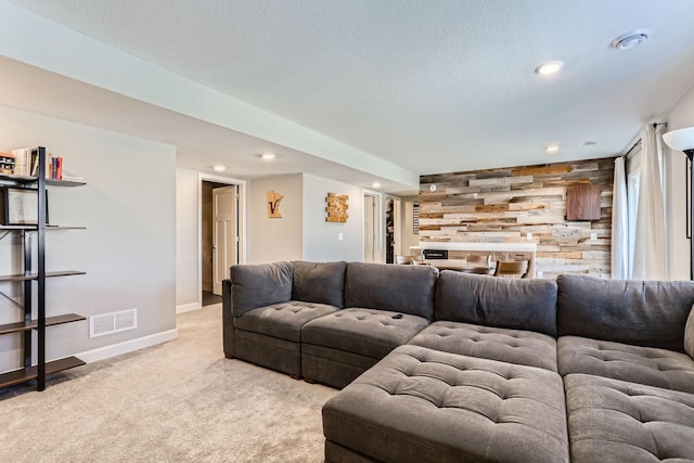 living area with visible vents, wood walls, an accent wall, baseboards, and light colored carpet