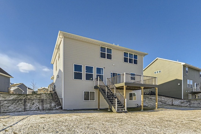 back of property with a deck, fence, and stairs