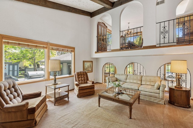 carpeted living area with a high ceiling, beamed ceiling, a chandelier, and arched walkways