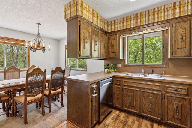 kitchen featuring dishwasher, a textured ceiling, a sink, a chandelier, and hanging light fixtures