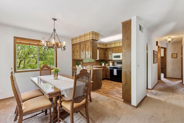 dining room with light carpet, a chandelier, a textured ceiling, and baseboards