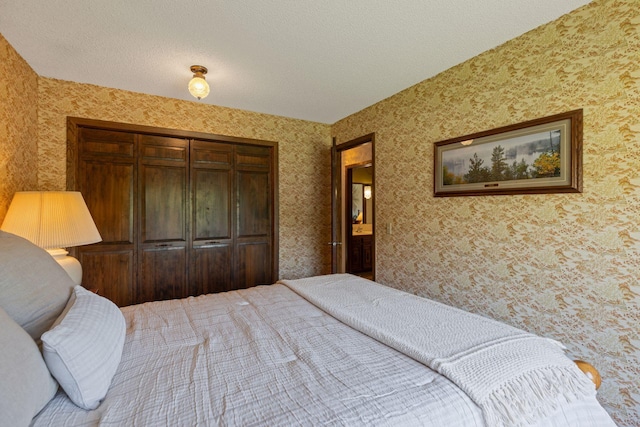 bedroom featuring wallpapered walls, a closet, and a textured ceiling