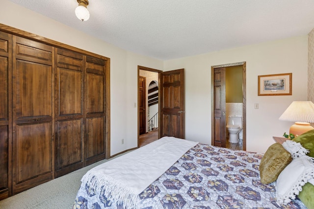 bedroom with a closet, carpet flooring, ensuite bathroom, and a textured ceiling