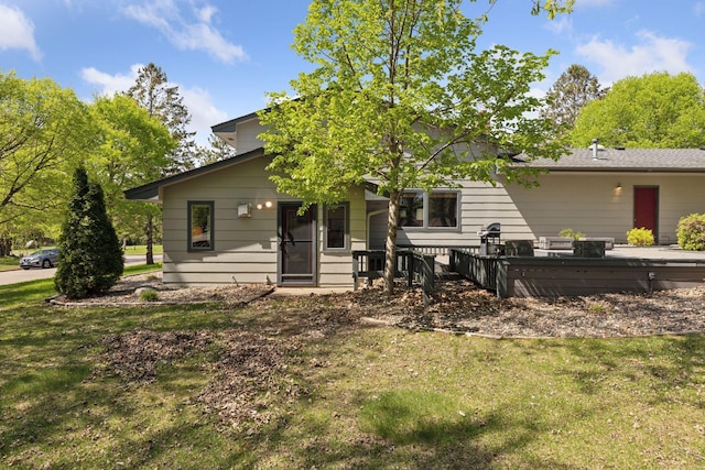 rear view of house featuring a lawn and a deck