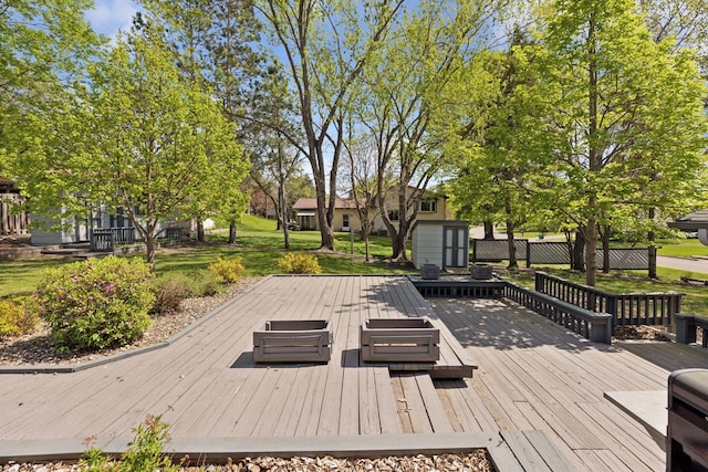 wooden deck featuring a storage shed, an outbuilding, and a lawn