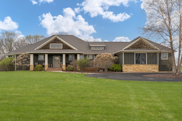 craftsman inspired home with covered porch, stone siding, and a front yard