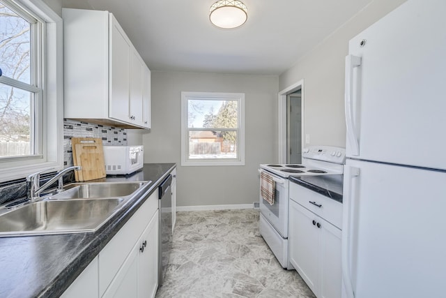 kitchen featuring a sink, white appliances, white cabinetry, and dark countertops