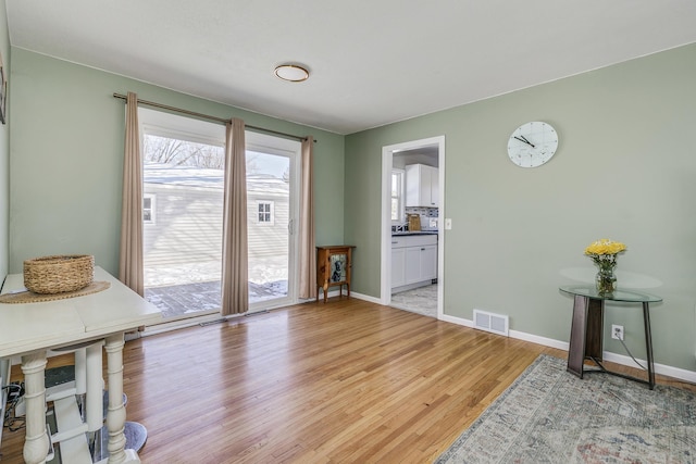 dining space with visible vents, light wood-style flooring, and baseboards