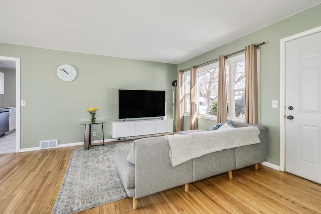 living area featuring baseboards, visible vents, and wood finished floors