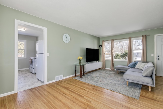 living area with baseboards, visible vents, and wood finished floors