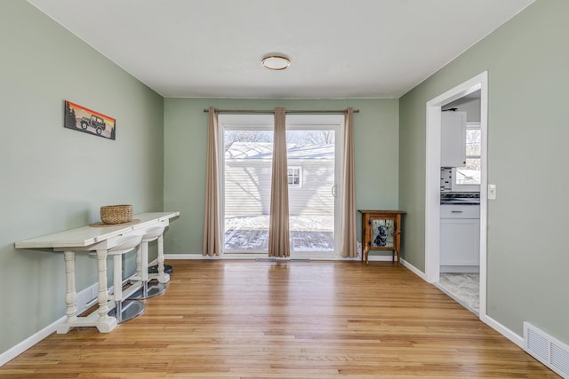 doorway with light wood-style floors, visible vents, and baseboards