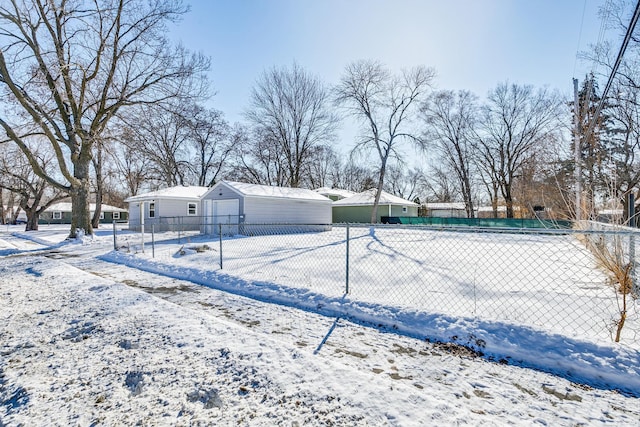 yard covered in snow featuring an outbuilding, fence, and a garage