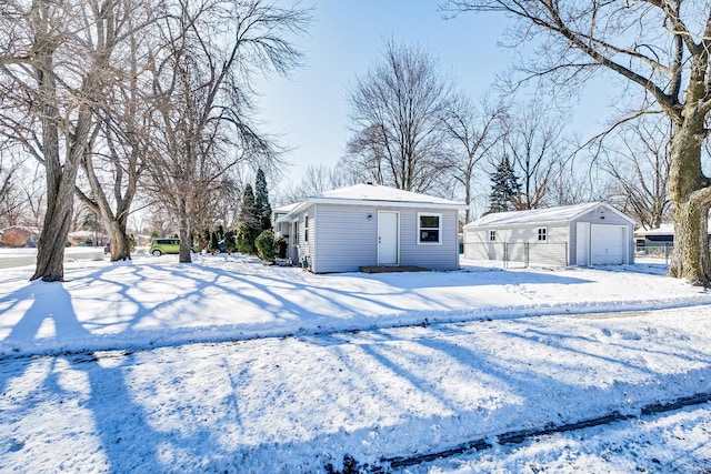 snowy yard with a garage and an outbuilding