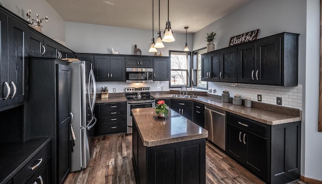 19288 Evenston Dr, Farmington, MN 55024 - kitchen with stainless steel appliances, a kitchen island, decorative backsplash, dark cabinets, and a sink