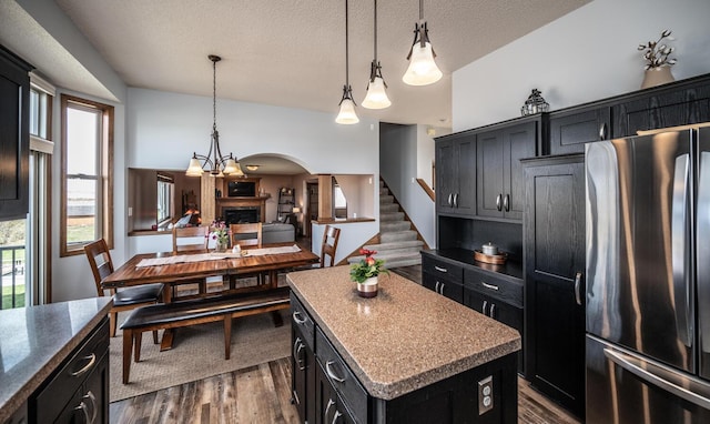 19288 Evenston Dr, Farmington, MN 55024 - kitchen with freestanding refrigerator, dark cabinetry, a center island, dark wood-style floors, and a textured ceiling