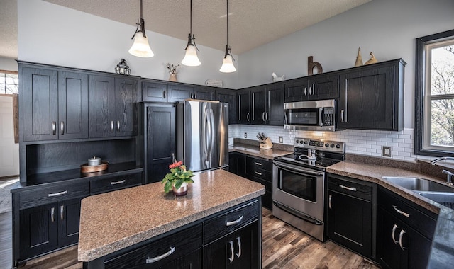 19288 Evenston Dr, Farmington, MN 55024 - kitchen with appliances with stainless steel finishes, dark cabinets, a sink, backsplash, and hanging light fixtures
