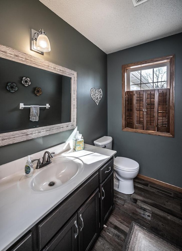 19288 Evenston Dr, Farmington, MN 55024 - bathroom with wood finished floors, vanity, toilet, a textured ceiling, and baseboards