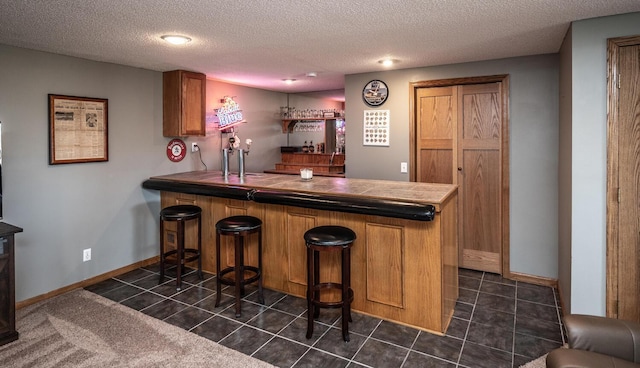 19288 Evenston Dr, Farmington, MN 55024 - indoor dry bar with dark tile patterned floors, a textured ceiling, and baseboards