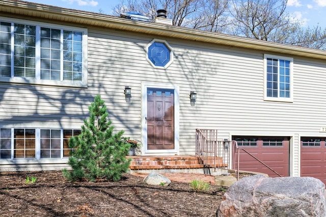 view of exterior entry featuring a garage and a chimney