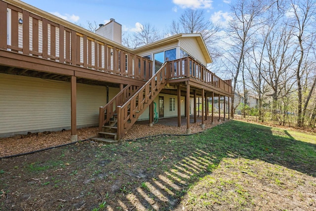 back of house featuring a yard, stairway, a wooden deck, and a chimney