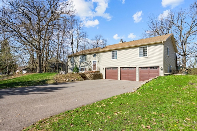 view of front of home featuring a garage, aphalt driveway, a front yard, and a chimney
