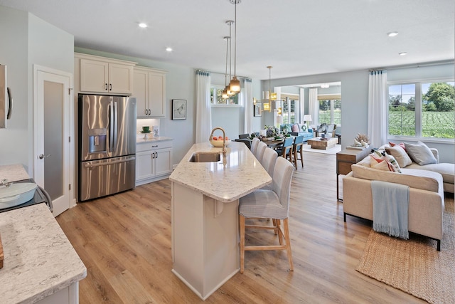 2717 Kalland Ave NE, Saint Michael, MN 55376 - kitchen featuring stainless steel fridge with ice dispenser, a sink, open floor plan, light wood finished floors, and a kitchen bar