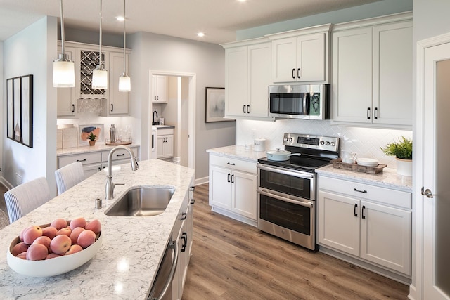 2717 Kalland Ave NE, Saint Michael, MN 55376 - kitchen with stainless steel appliances, a sink, light wood-style flooring, decorative backsplash, and recessed lighting