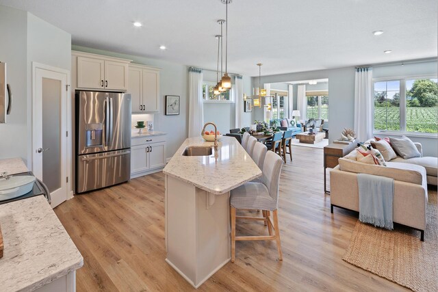 2717 Kalland Ave NE, Saint Michael, MN 55376 - kitchen featuring stainless steel fridge with ice dispenser, a sink, open floor plan, light wood-type flooring, and a kitchen breakfast bar