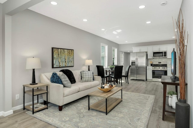 living area featuring light wood finished floors, recessed lighting, and baseboards