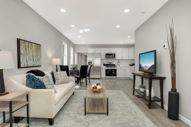 living room with light wood-style flooring, recessed lighting, and baseboards