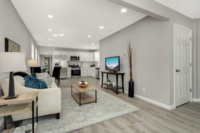 living room with light wood-type flooring, recessed lighting, and baseboards