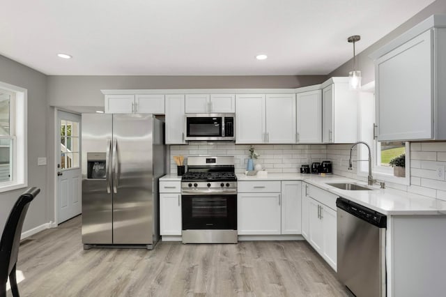 kitchen featuring stainless steel appliances, a sink, light countertops, backsplash, and recessed lighting