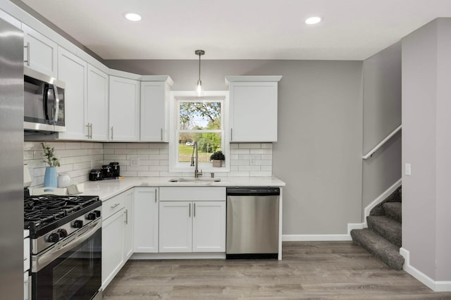 kitchen with stainless steel appliances, a sink, decorative backsplash, baseboards, and recessed lighting
