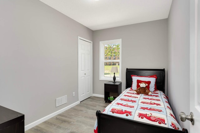 bedroom featuring light wood-type flooring, baseboards, and a closet