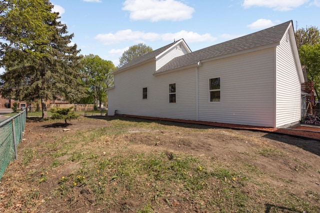 view of side of home with fence and a shingled roof