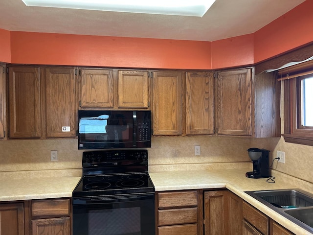 kitchen with a sink, decorative backsplash, light countertops, and black appliances