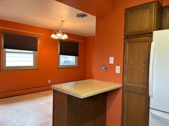 kitchen featuring a peninsula, freestanding refrigerator, a notable chandelier, visible vents, and decorative light fixtures